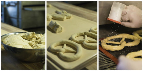 Unbaked pretzels being dipped in lye solution before going into the oven